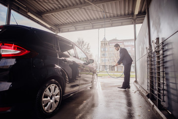 Portrait of happy businessman standing next to his clean car.