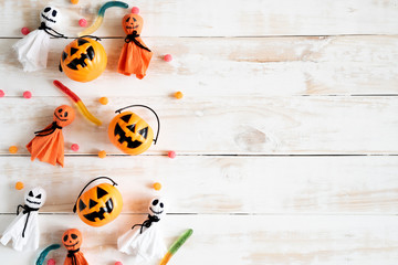 Top view of white ghost  and yellow pumpkins with jelly worm on white wooden background. halloween concept.