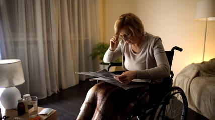 Old female trying to read newspaper in eyeglasses, eye problem, blurred vision
