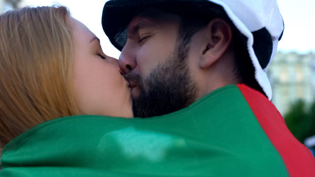 Cheerful football fans kissing in crowd, rejoicing victory of favorite team