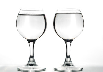 Two round glasses empty or full with waves of liquid on a white background