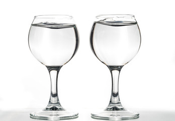 Two round glasses empty or full with waves of liquid on a white background