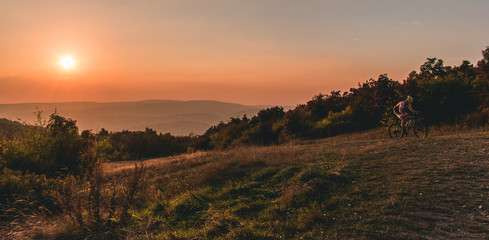 Cycling man with a setting sun behind him