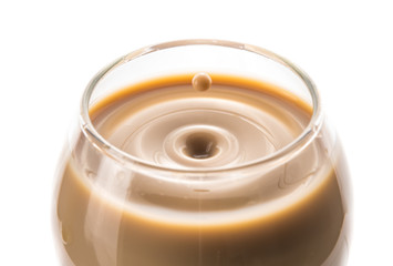 A drop of chocolate liquor dropped into a round glass left waves and a splash