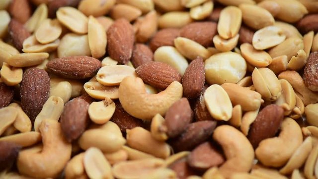 Closeup of cocktail Macadamias and cashew nut and peanut and almond mixed bean with salted in rotating motion. Food eaten with alcoholic drinks concept. Benefit of protein theme.
