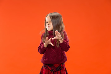 Angry teen girl standing on trendy studio background. Female half-length portrait. Human emotions, facial expression concept. Front view.