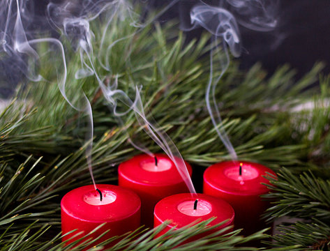 spruce green branch and red extinct advent candles from which smoke comes