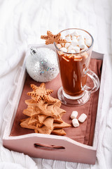 Cup of hot chocolate with marshmallow and gingerbread cookies on tray