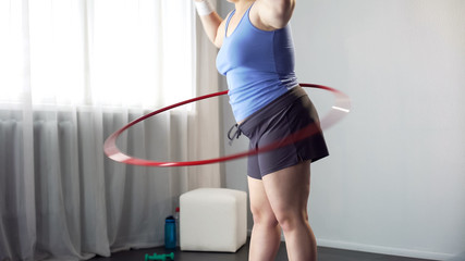 Overweight female twirling hula hoop, exercise for weight loss, slimming process