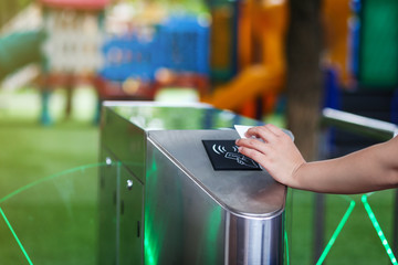 Close-up hand with keycard at pedestrian access control flap barriers.