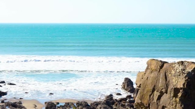 A Cliff out if focus with the sea bellow on a beach in Cornwall Bude