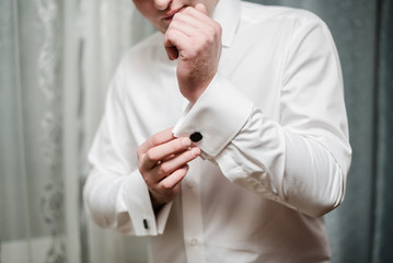 groom puts on cufflinks, man in white shirt, groom's fees