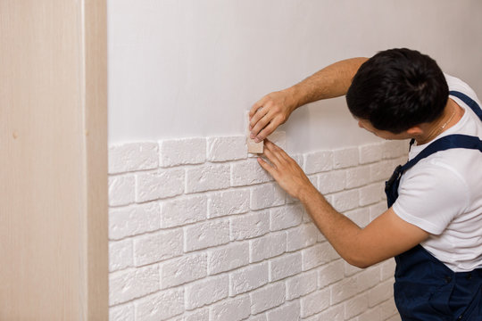 Professional Builder gluing decorative tile on wall.