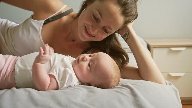 A Portrait of a beautiful mother with her 2 month old baby in the bedroom