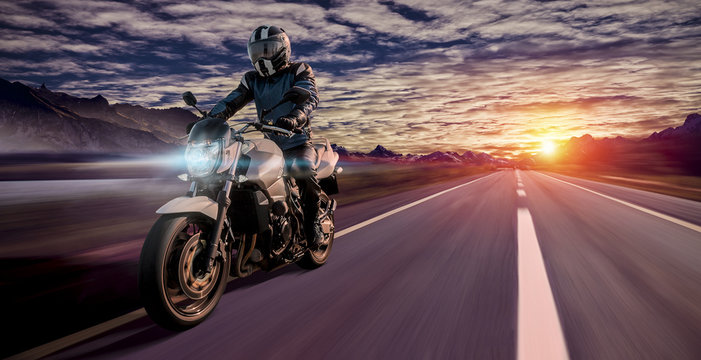 motorcyclist rides home in the evening on a highway while sunset © vizualni