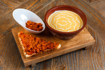 Cheese cream soup stands on a wooden tray with a piece of bread