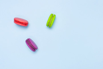 Sweet macaroons on blue background top view flat lay. Delicious breakfast, beautiful dessert, colorful almond cookies, pastel colors.