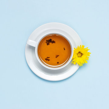 Cup of herbal tea with a yellow chrysanthemum on blue background top view flat lay. Concept Good morning, Greeting card, floral background, still life with tea cup