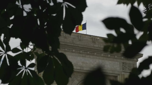 Hide view of Romanian Flg waving in a cloudy day on Arcul de Triumf. Bucharest, Romania