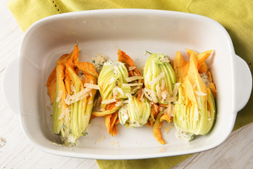 stuffed zucchini or courgette blossoms in a casserole dish on a green napkin, cooking a mediterranian appetizer, high angle view from above