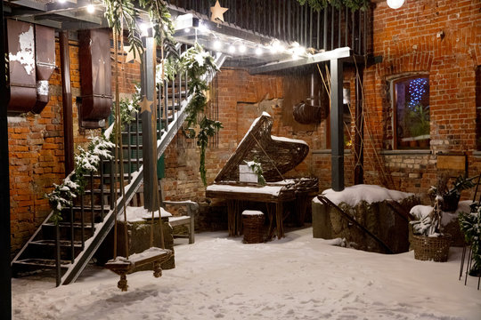old  snow yard with brick wall, grand piano, swing and Christmas decoration in the evening