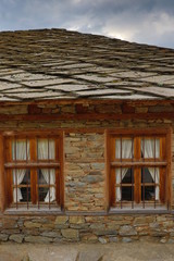 Fototapeta na wymiar Stone house with stone fence in the Village of Leshten. Historical, facade. The Village of Leshten is architectural reservation