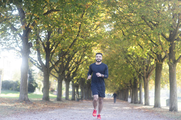 Junger sportlicher Mann joggt im Grünen