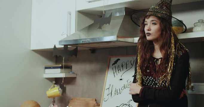 A scary masked witch playing with emotion , sitting on the kitchen table and changing the mood on sad to happy faces. Shot on Red Epic