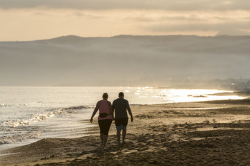 couple walking on the beach at sunrise