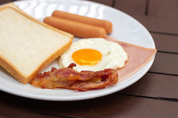 Simple breakfast. Toast bread, fried egg, sausage, ham and bacon.