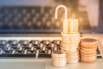 Business, technology, saving and security Concept. Close up of unlock master key on stack of coins on laptop computer notebook.