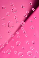 close-up view of transparent clean dew drops on pink background