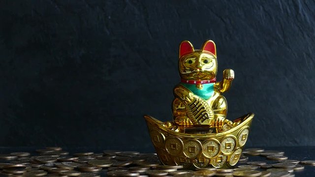Maneki Neko Japanese lucky cat waving paw and drops a lot of coins for money luck.Slow motion video