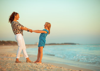 mother and daughter on seacoast in evening having fun time