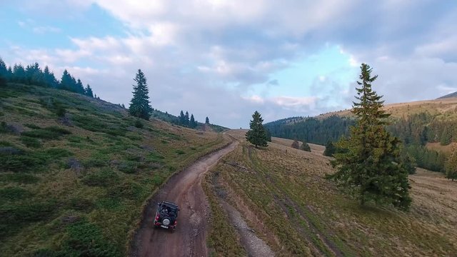 Aerial drone tracking shot driving suzuki jimny off-road car on mountain road 