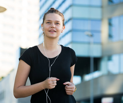 Girl enjoying morning run outdoors with music