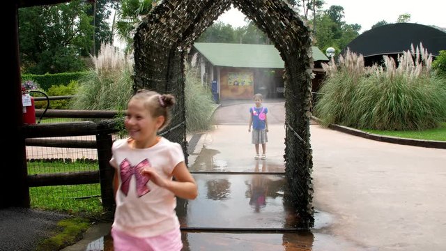SAFARI PARK POMBIA, ITALY - JULY 7, 2018: entertainment at the zoo. light air drizzle. water is sprayed in a small corridor through which cheerful children run.