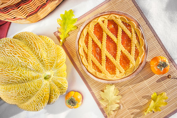 shortbread cake with persimmon filling on a rug surrounded by yellow leaves, persimmon and melon