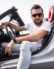 close up.stylish young man sitting in a luxury car