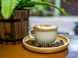 Cup of cappuccino coffee on wooden table in cafe.