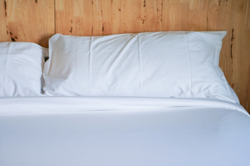 White pillow on bed with wooden wall.