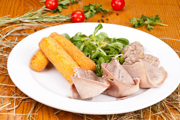 Salad with beef tongue, beef tartare, cheese sticks and  lamb’s lettuce on white plate. Close up