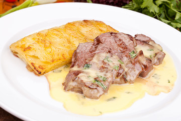 Beef tenderloin with potato pie on white plate. Close up