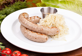German sausages with sauerkraut on white plate. Close up