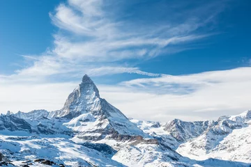 Foto auf Acrylglas Matterhorn Malerischer Blick auf den schneebedeckten Gipfel des Matterhorns an sonnigen Tagen mit blauem Himmel und dramatischen Wolken im Hintergrund, Schweiz.