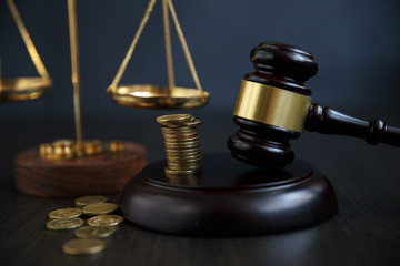 Close-up Of A Judge's Hand Holding Gavel Over Stacked Golden Coins