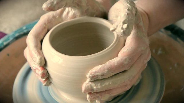 Woman girl her hands dub wall jug, sculpts out of clay on circle. Workshop on sculpt white clay closeup. Dirty hands in the clay. Making ceramic products. Artistic creative. Craft.