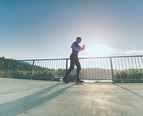 Attractive man jogging against to sun. Regular morning training