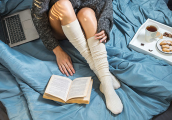 Beautiful Legs close-up in bed, girl with a cup of tea and reading a book.