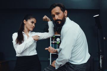 Male and female colleagues demonstrate muscles power in office. Fight of genders concept.